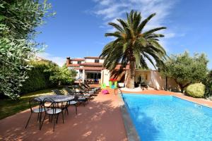 basen ze stołami i krzesłami oraz palmą w obiekcie Holiday Home Villa Margherita w Puli