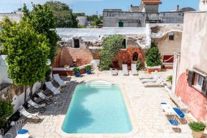 una piscina in un cortile con sedie e un edificio di Masseria La Macchiola & Corti del Mito a Spongano