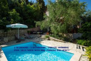 a swimming pool with an umbrella next to a house at Evridiki's Villas in Agios Nikitas