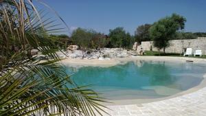 a swimming pool in a yard with two white chairs at Agriturismo Kypeiros in Noto