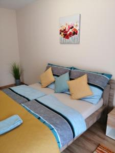 duże łóżko z niebieskimi i żółtymi poduszkami w obiekcie Boglárka Apartman w Segedynie