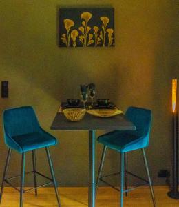 stół z 2 niebieskimi krzesłami i stół z jedzeniem w obiekcie Paradis Secret w mieście Beyne-Heusay