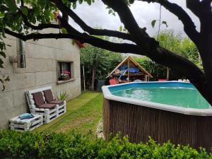 een achtertuin met een zwembad en twee stoelen en een huis bij A Chabola Mondariz in Pontevedra