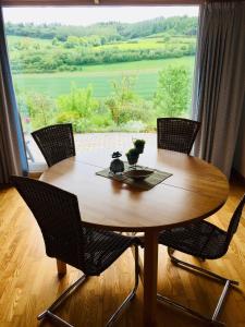 une table en bois avec des chaises et une grande fenêtre dans l'établissement Idyllisch Wohnen im Weserbergland - Bungalow mit phantastischer Aussicht für 4 Personen, à Polle