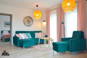ein Wohnzimmer mit einem blauen Sofa und einem Tisch in der Unterkunft Pod Brzozami Apartamenty 5 Mórz in Ustronie Morskie