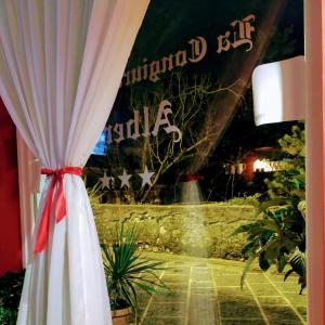 a window with a white curtain with a red bow at Hotel La Congiura dei Baroni in Teggiano