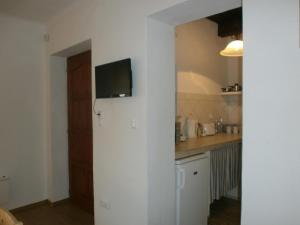 a kitchen with a tv on a white wall at Ninszianna Apartman in Hegyhátszentjakab