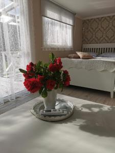 a vase with red flowers on a table in a bedroom at Sapņi in Kolka