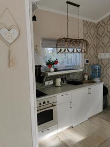 a kitchen with white cabinets and a chandelier at Sapņi in Kolka
