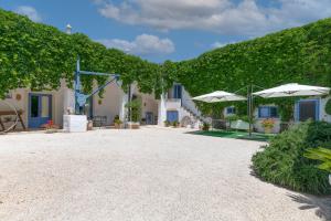 una casa con patio e ombrelloni nel cortile di Masseria La Macchiola & Corti del Mito a Spongano