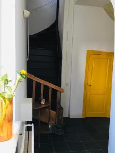 a hallway with a yellow door and a staircase at Stadsvilla met patio in centrum Maastricht in Maastricht