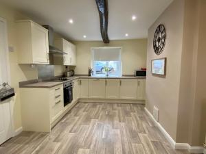 a large kitchen with white cabinets and a window at Rattlebeck Farm Cottage and Hot Tub PET FRIENDLY in Welton