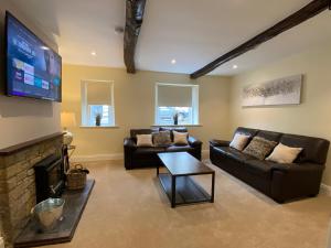 a living room with two couches and a flat screen tv at Rattlebeck Farm Cottage and Hot Tub PET FRIENDLY in Welton