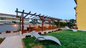 a backyard with a wooden pergola and a table and chairs at Apartments Dario in Medulin