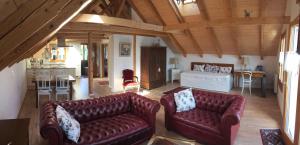 a living room with two leather couches and a kitchen at Haus am See in Därligen