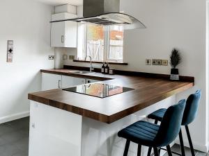 a kitchen with a counter with two blue chairs at 4 bed family home wifi, netflix, parking, close to wicksteed park in Kettering