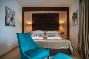 a bedroom with a bed and a blue chair at Hotel Meduza in Senj