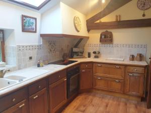 a kitchen with wooden cabinets and a sink at La GRANGE de MOMBEL in Losse