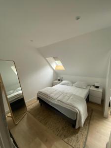ein weißes Schlafzimmer mit einem Bett und einem Spiegel in der Unterkunft Appartement vue Port in Boulogne-sur-Mer