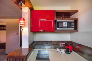 a kitchen with red cabinets and a microwave at Apartament Podwale in Łańcut