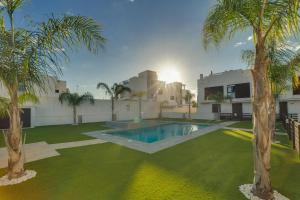 a backyard with a swimming pool and palm trees at Bahia Homes Residencial in La Horadada