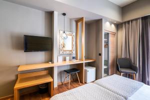 a bedroom with a bed and a desk with a television at Agamemnon Hotel in Nafplio