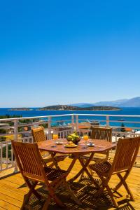 a wooden table and chairs on a deck with a view of the ocean at Eleni's Cozy House in Agios Nikolaos