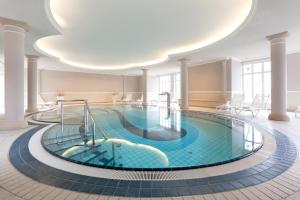 a pool in the middle of a building with a large ceiling at Vju Hotel Rügen in Göhren