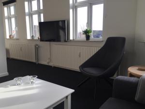Pokój z krzesłem, stołem i telewizorem w obiekcie Siesta Vejle w mieście Vejle