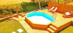 a wooden deck with a swimming pool and two chairs at River House - Casas do Rio Tora in Arcos de Valdevez