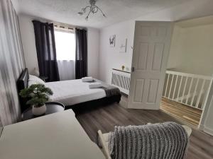 a bedroom with a bed and a chair and a door at Glasgow Apartment Cozy and ultramodern in Glasgow