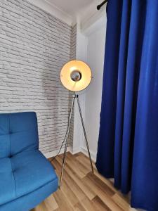 una lámpara y una silla azul en una habitación con una pared de ladrillo en Glasgow Apartment Cozy and ultramodern en Glasgow