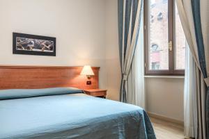 a bedroom with a blue bed and a window at Hotel Impero in Cremona