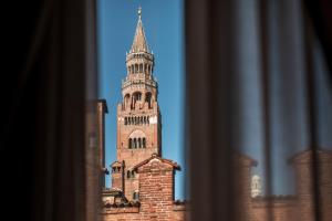 un alto edificio in mattoni con torre dell'orologio di Hotel Impero a Cremona