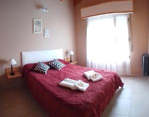 a bedroom with a red bed with two towels on it at Cabañas Los Troncos in Sierra de la Ventana