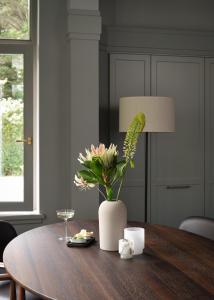 une table en bois avec un vase et des fleurs. dans l'établissement Benedict Noordwijk, à Noordwijk aan Zee