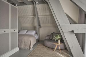 a attic bedroom with a bed and a chair at Boutique Hotel Benedict Noordwijk in Noordwijk aan Zee