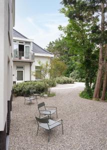 a group of chairs sitting on a gravel patio at Boutique Hotel Benedict Noordwijk in Noordwijk aan Zee