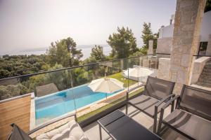 a house with a balcony with a swimming pool at Allure Luxury Villas in Skiathos