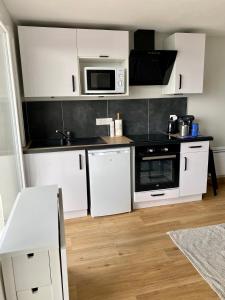 a kitchen with white cabinets and a microwave at Les Vies en Rose in Évian-les-Bains