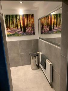a bathroom with two paintings of trees and a radiator at Boardinghouse Saargau in Überherrn
