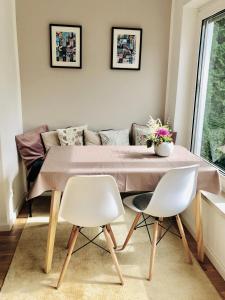 uma sala de estar com uma mesa e duas cadeiras brancas em urbanAPARTMENT No.2 Memmingen em Memmingen