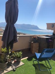 een patio met een parasol, een stoel en planten bij Sealoft in Isola delle Femmine