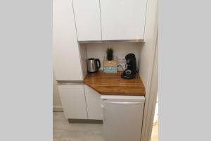 eine Küche mit weißen Schränken und einer Holzarbeitsplatte in der Unterkunft HanaHome 2 adultes parking privé business & tourisme in Le Chesnay + 5 Fotos