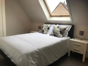 a bedroom with a large white bed with a skylight at Huis Marlin in De Haan
