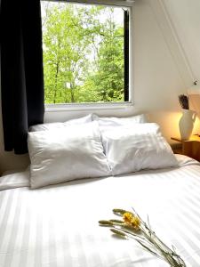 a white bed with a window and flowers on it at L'évasion - Bungalow 102 in Durbuy