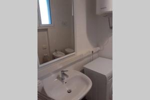 a white bathroom with a sink and a mirror at Dalla Bosh 2 in Parma