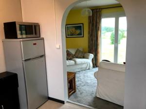 a kitchen with a refrigerator and a living room at Le Cottage in Vinax