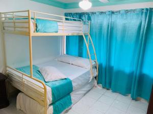 a bedroom with two bunk beds with blue curtains at La Gaviota B1 in Juan Dolio
