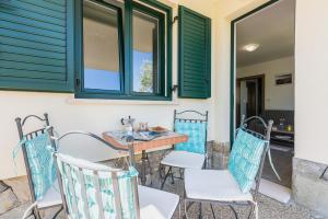 a patio with chairs and a table and windows at Apartments Garden in Baška
